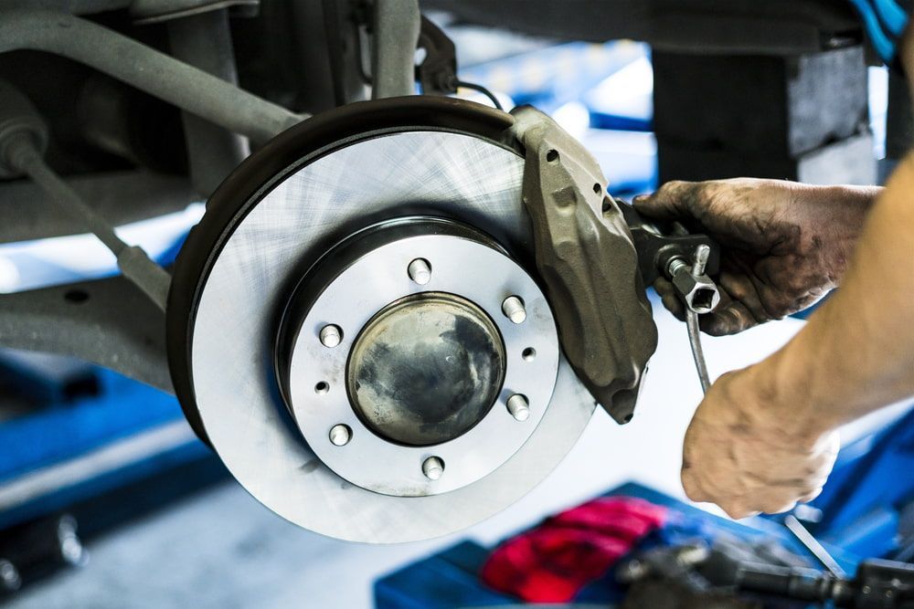 A Man is Working on a Brake Disc on a Car — Hancock Automotive in Bennetts Green, NSW