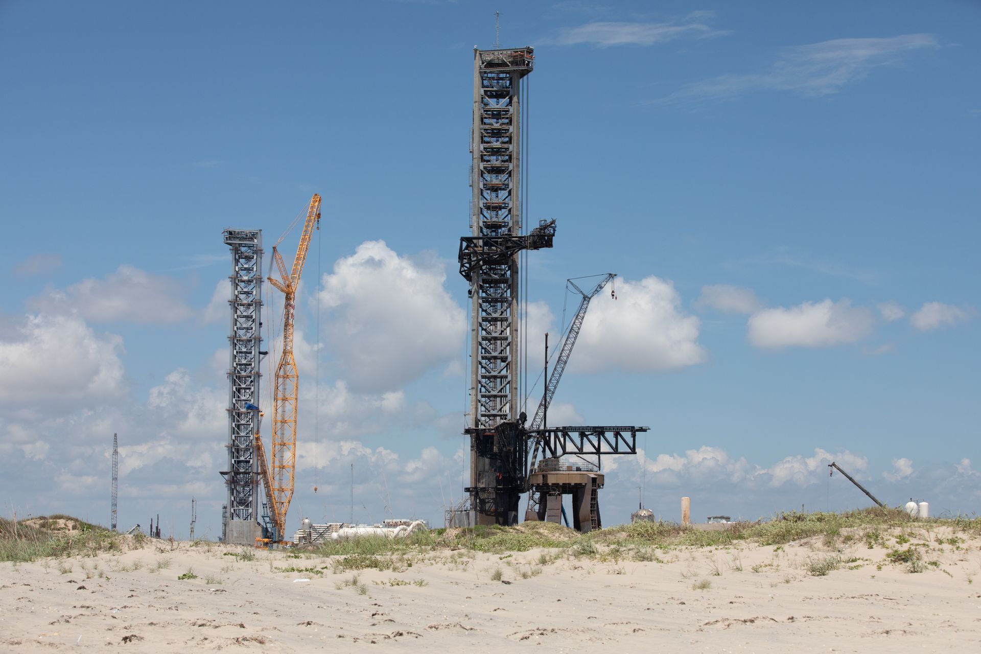 A large crane is sitting in the middle of a sandy field.