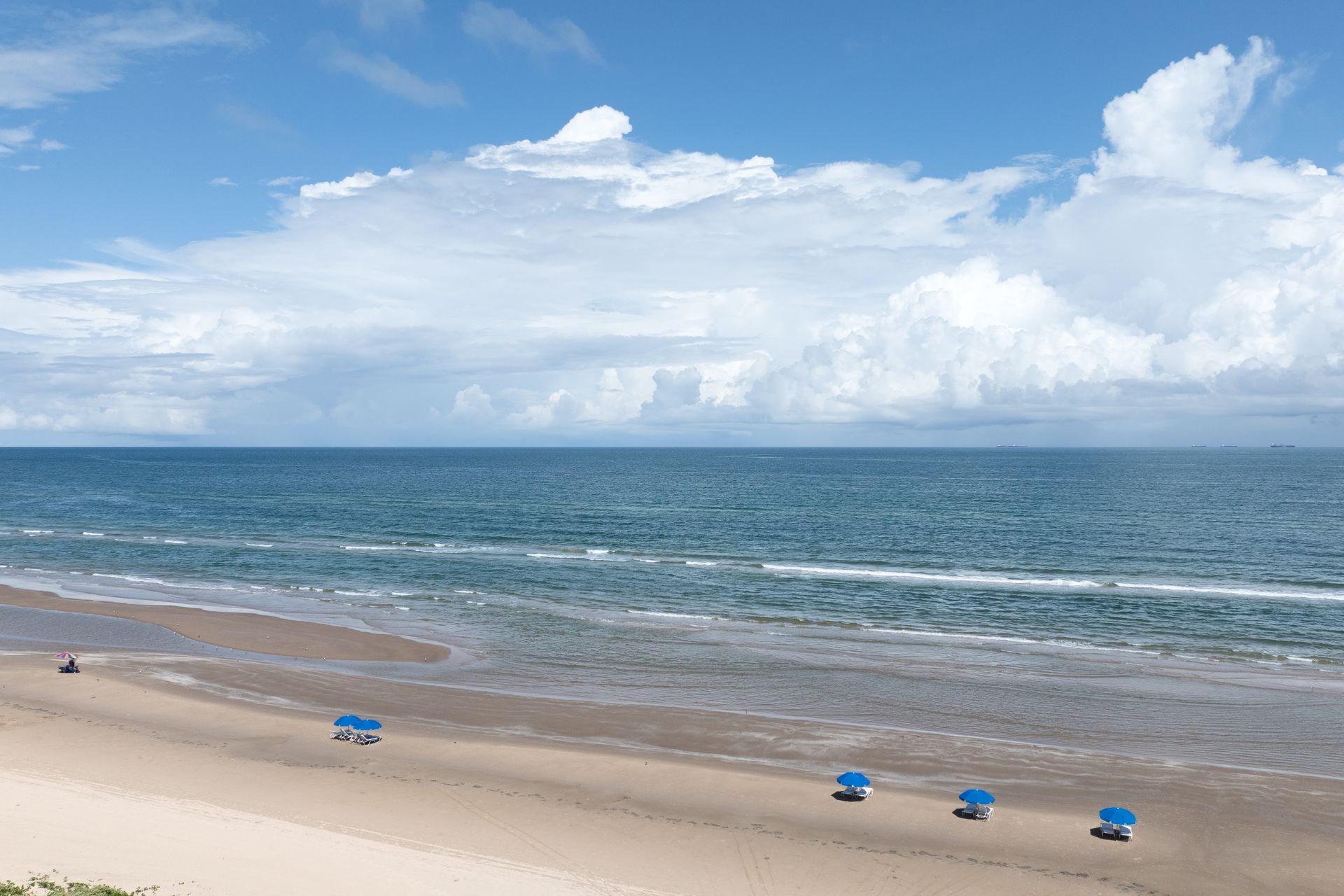 A beach with blue chairs and umbrellas on a sunny day.