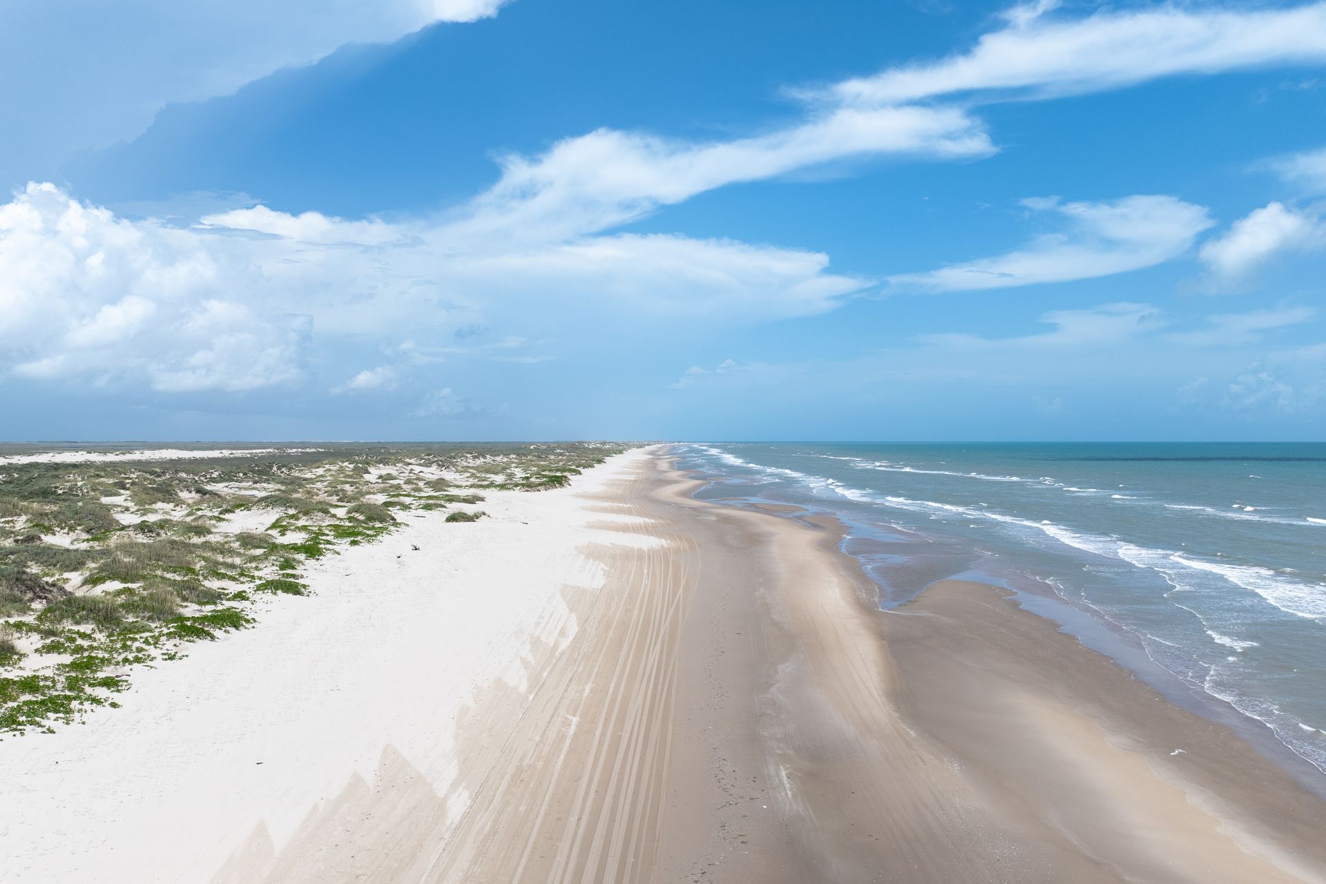 An aerial view of a long sandy beach leading to the ocean.