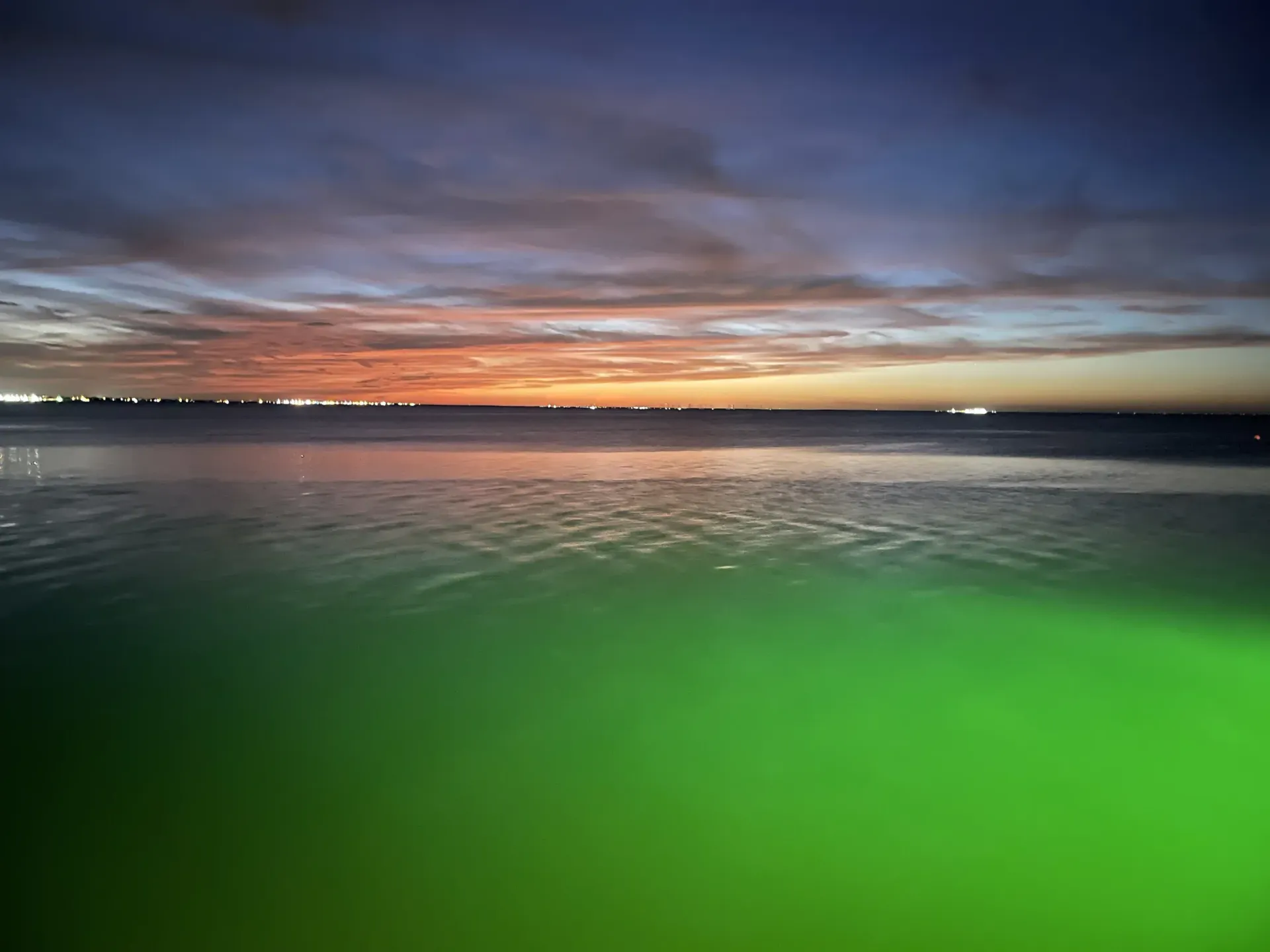 A sunset over a body of water with a green background.