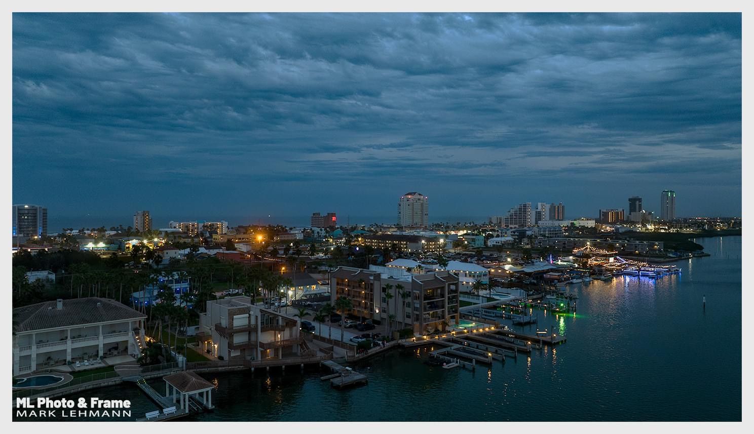 An aerial view of a city at night with a body of water in the foreground.