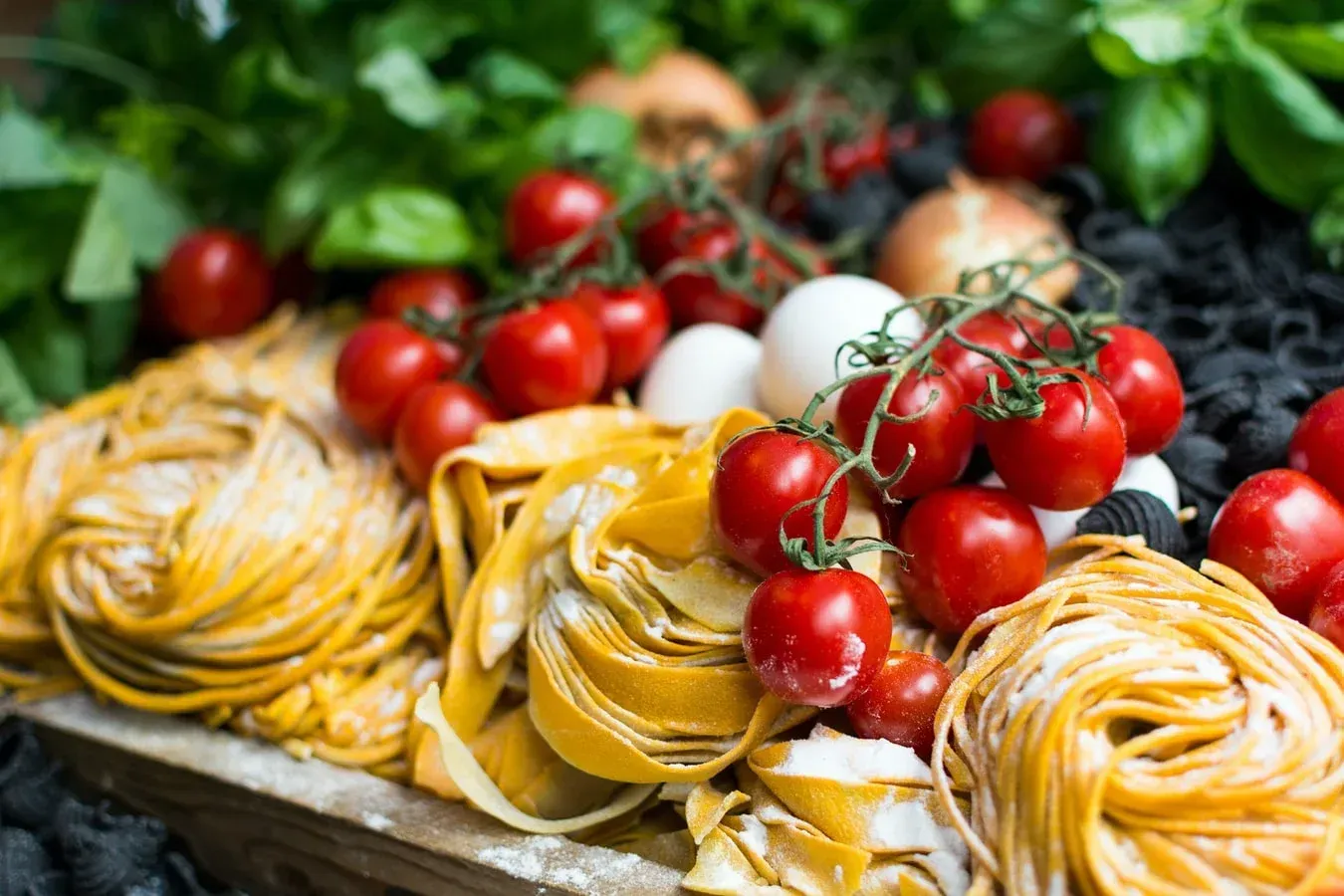 There are many different types of pasta and tomatoes on the table.