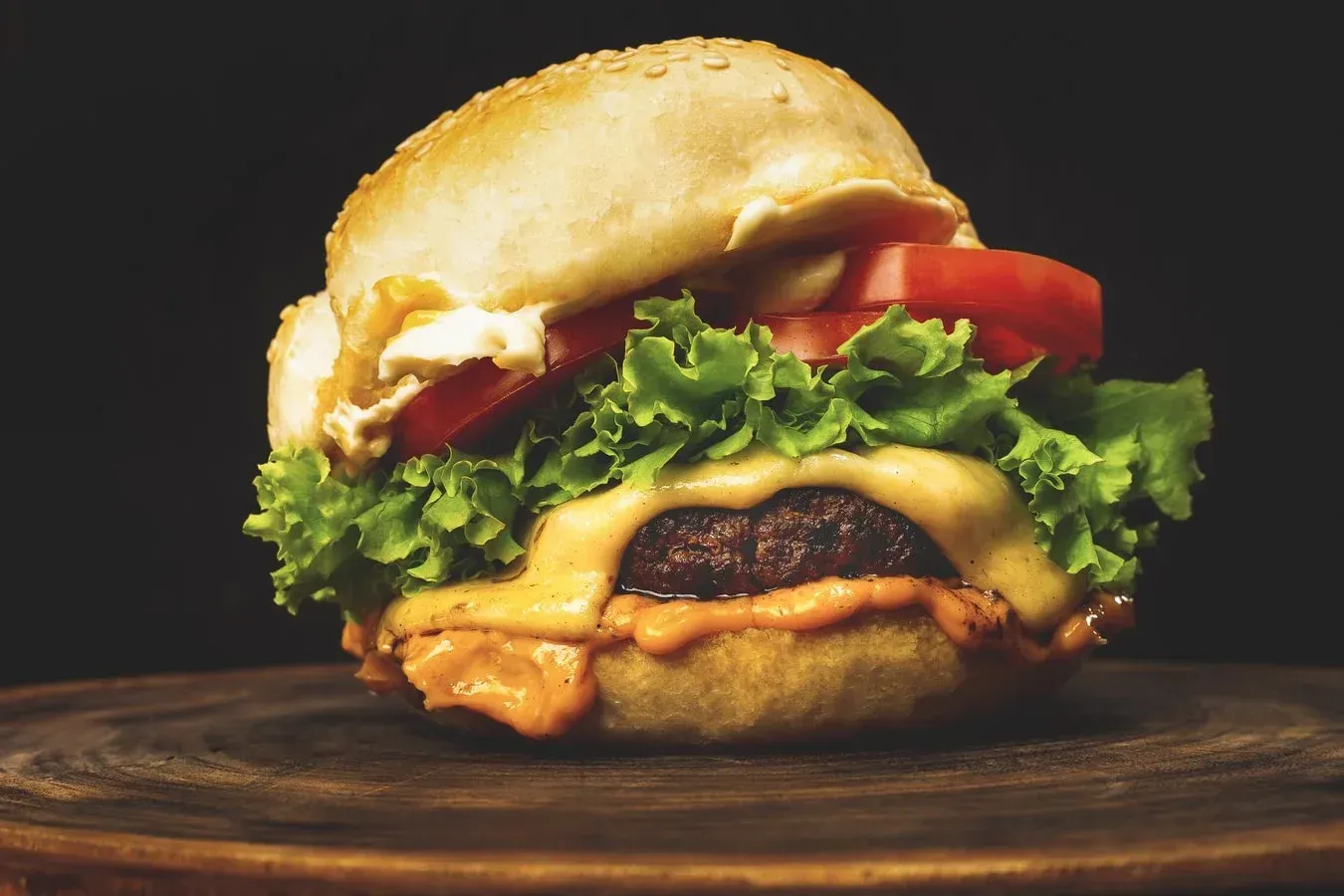 A close up of a hamburger on a wooden cutting board.