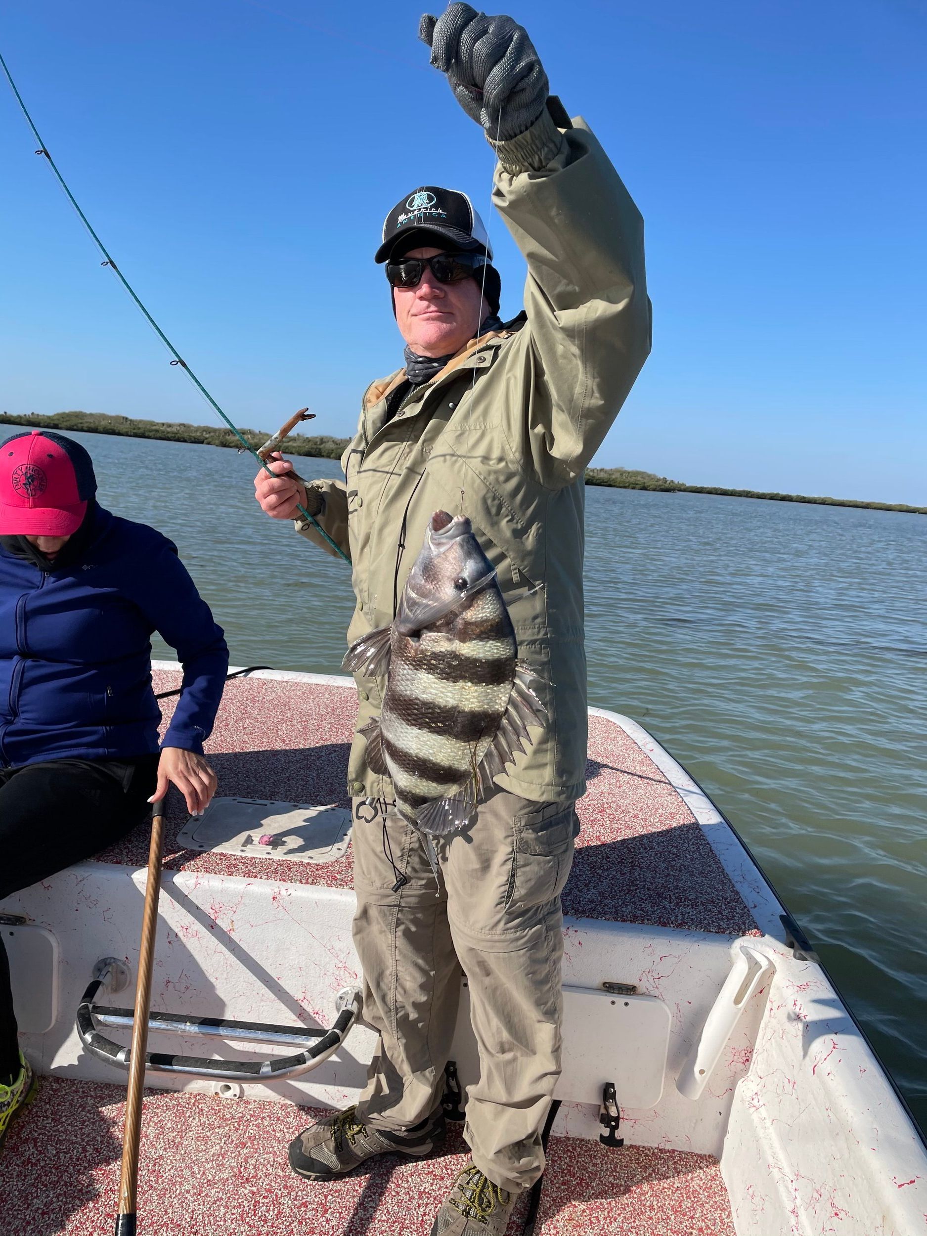 A man is standing on a boat holding a fish in his hand.