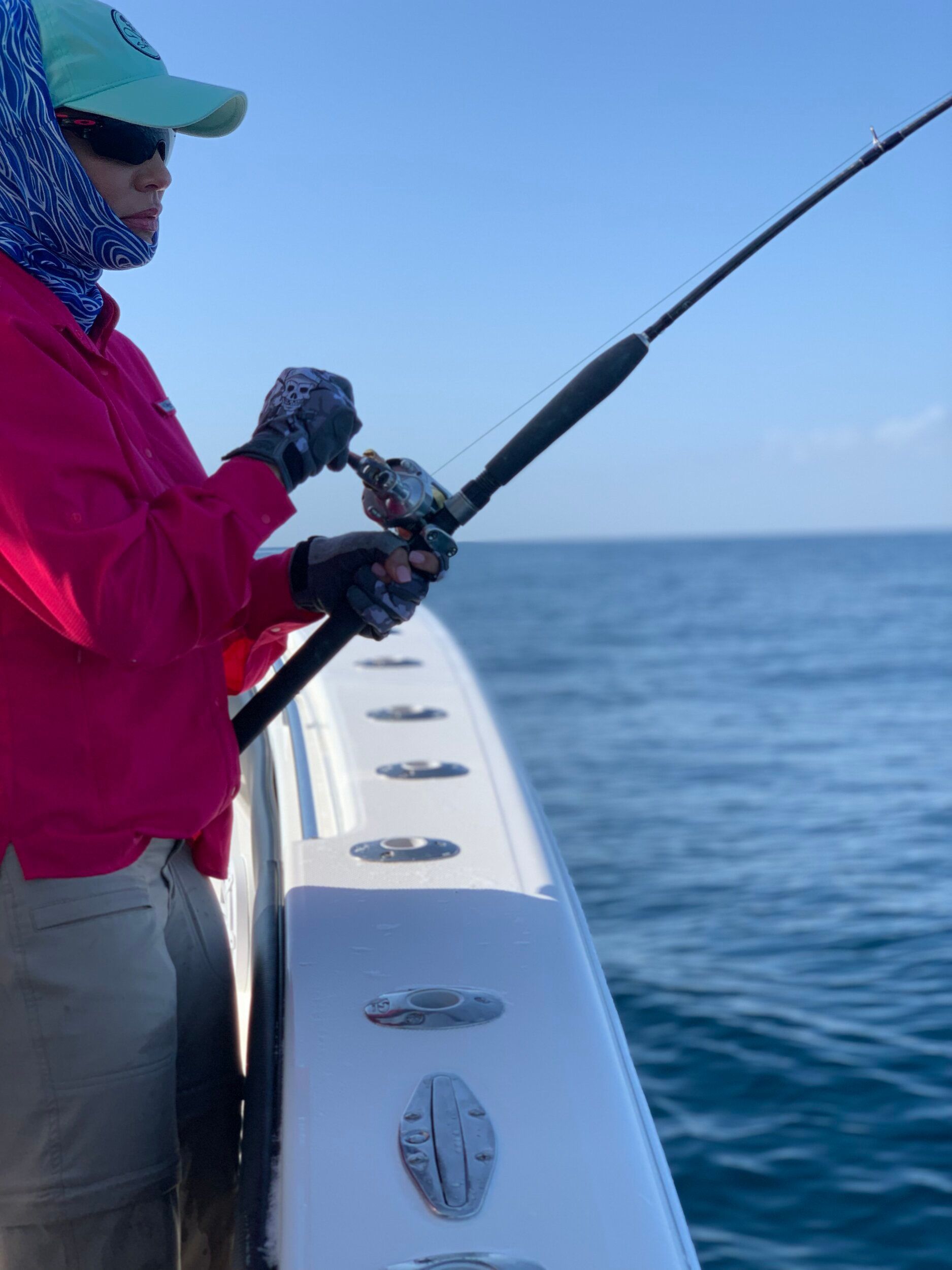 A woman in a pink shirt is fishing on a boat