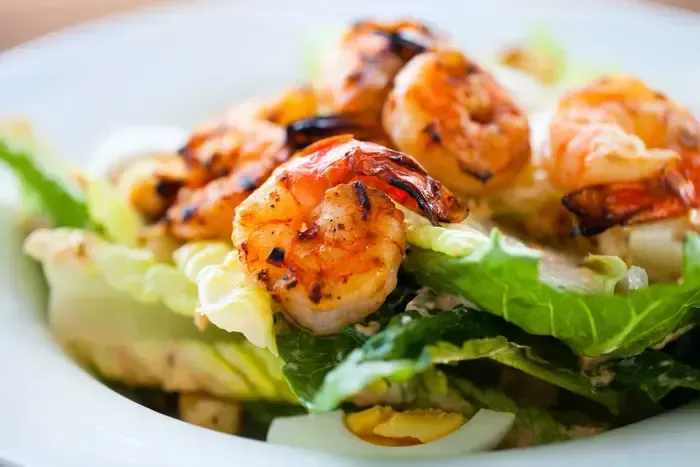 A close up of a salad with shrimp and lettuce on a plate.