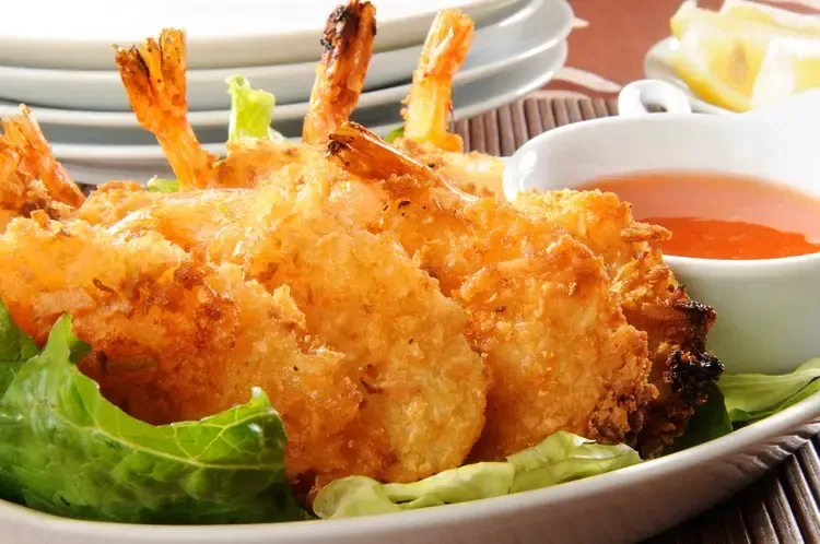 A plate of fried shrimp next to a bowl of dipping sauce