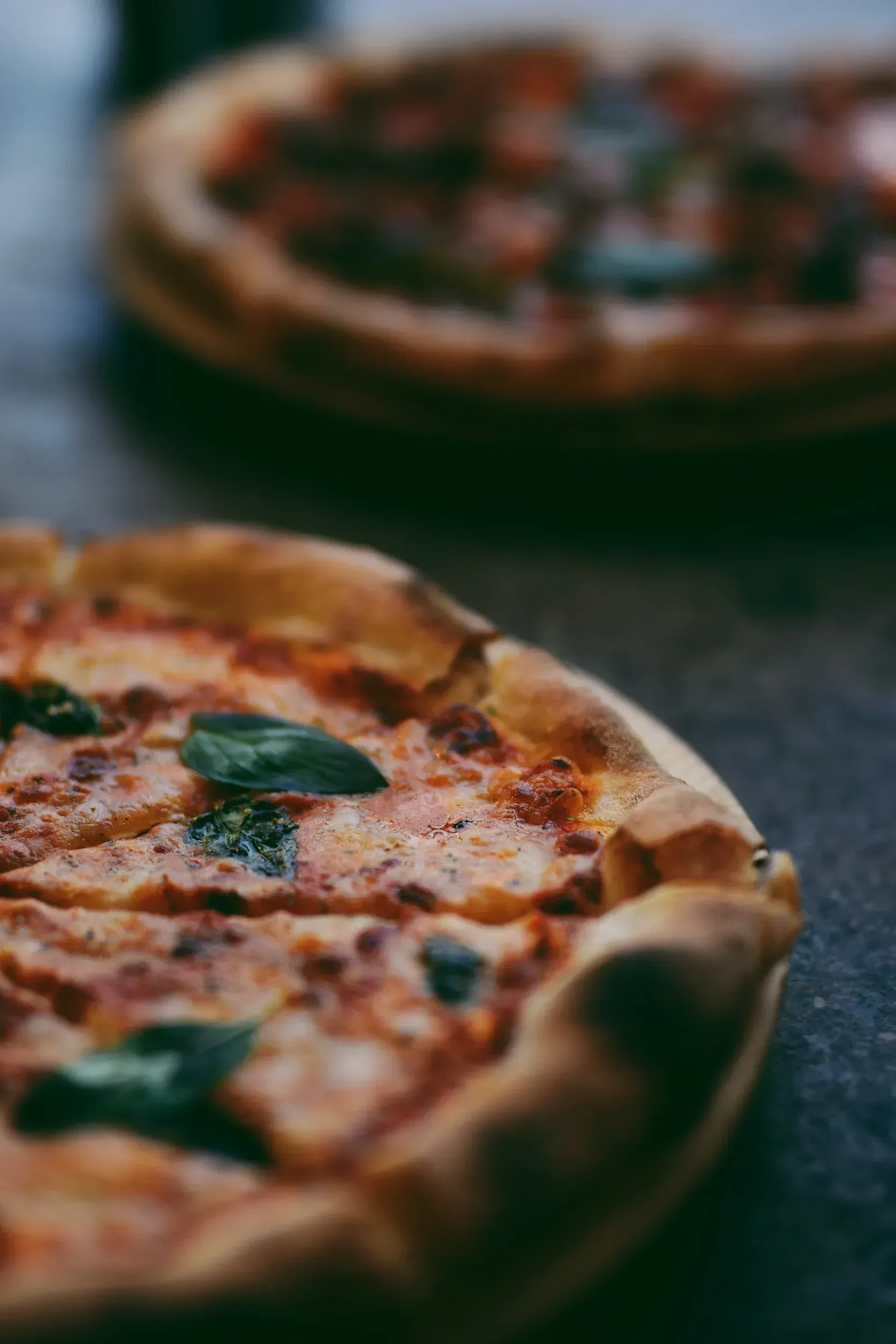 A close up of two pizzas on a table.