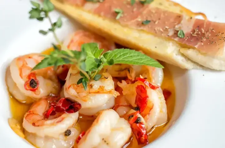 A close up of a plate of shrimp and bread on a table.