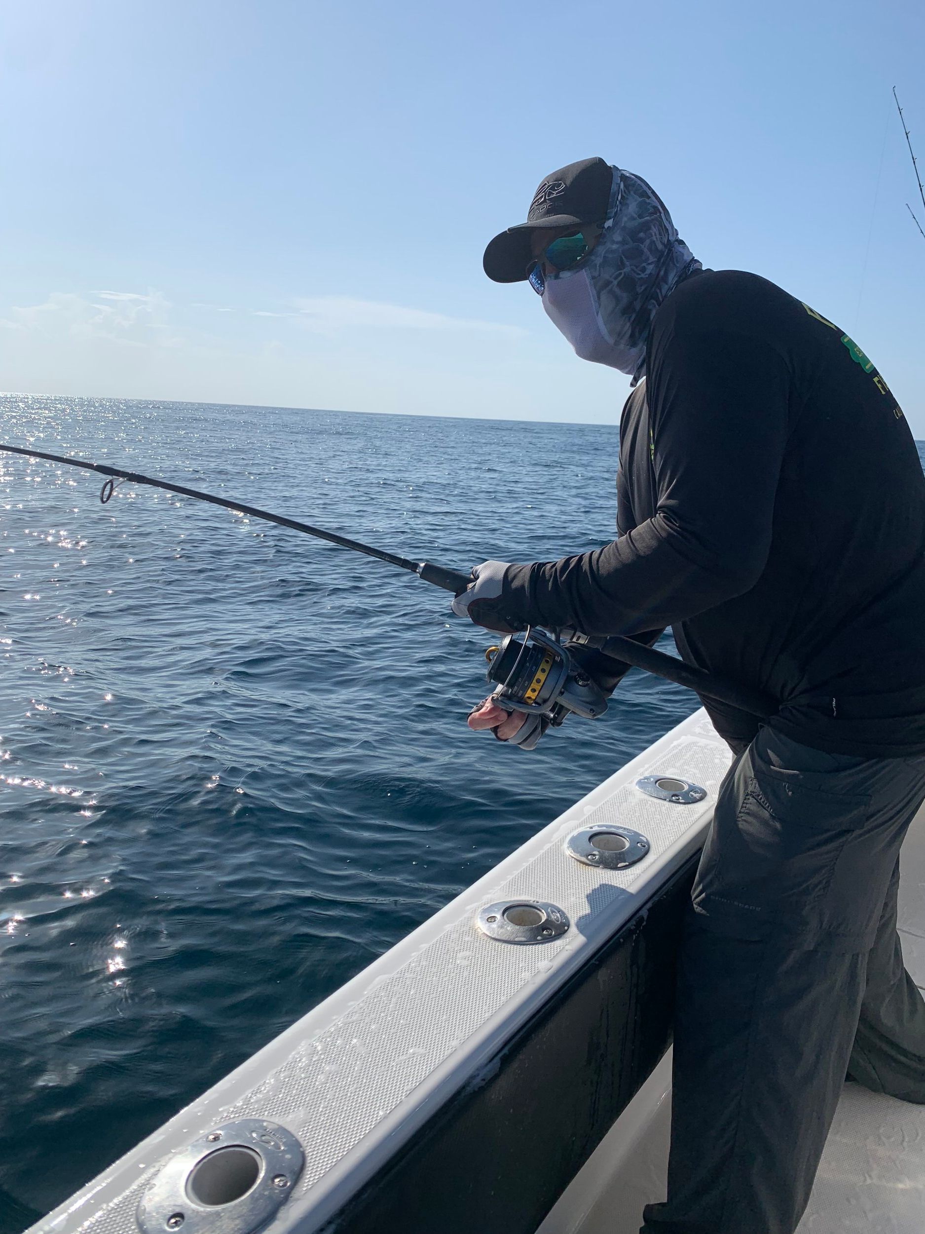 A man is fishing on a boat in the ocean.