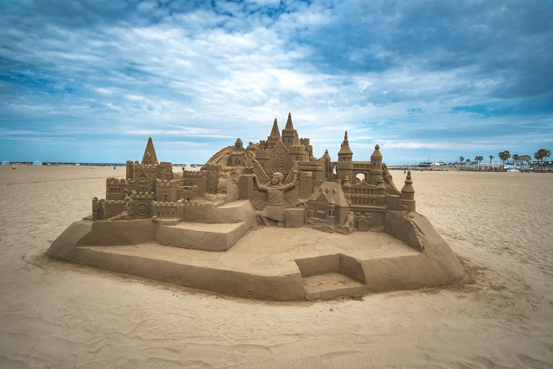 A large sand castle is sitting on top of a sandy beach.