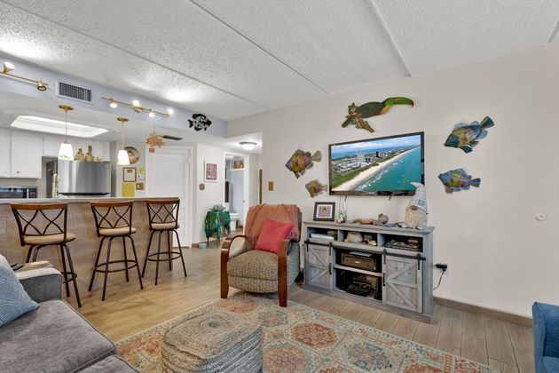 A living room with a couch , chair , television and bar stools.