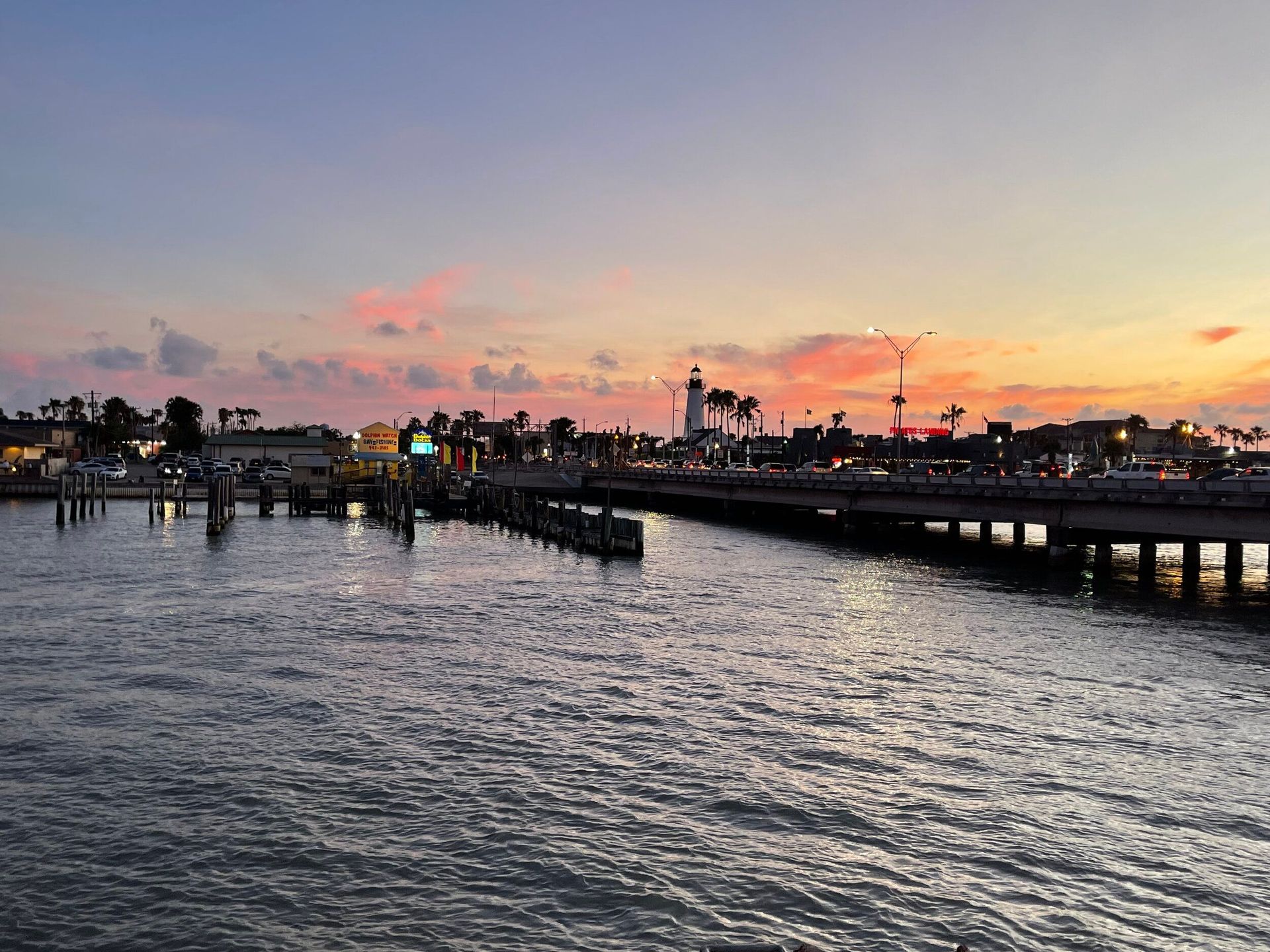 A sunset over a body of water with a lighthouse in the distance.