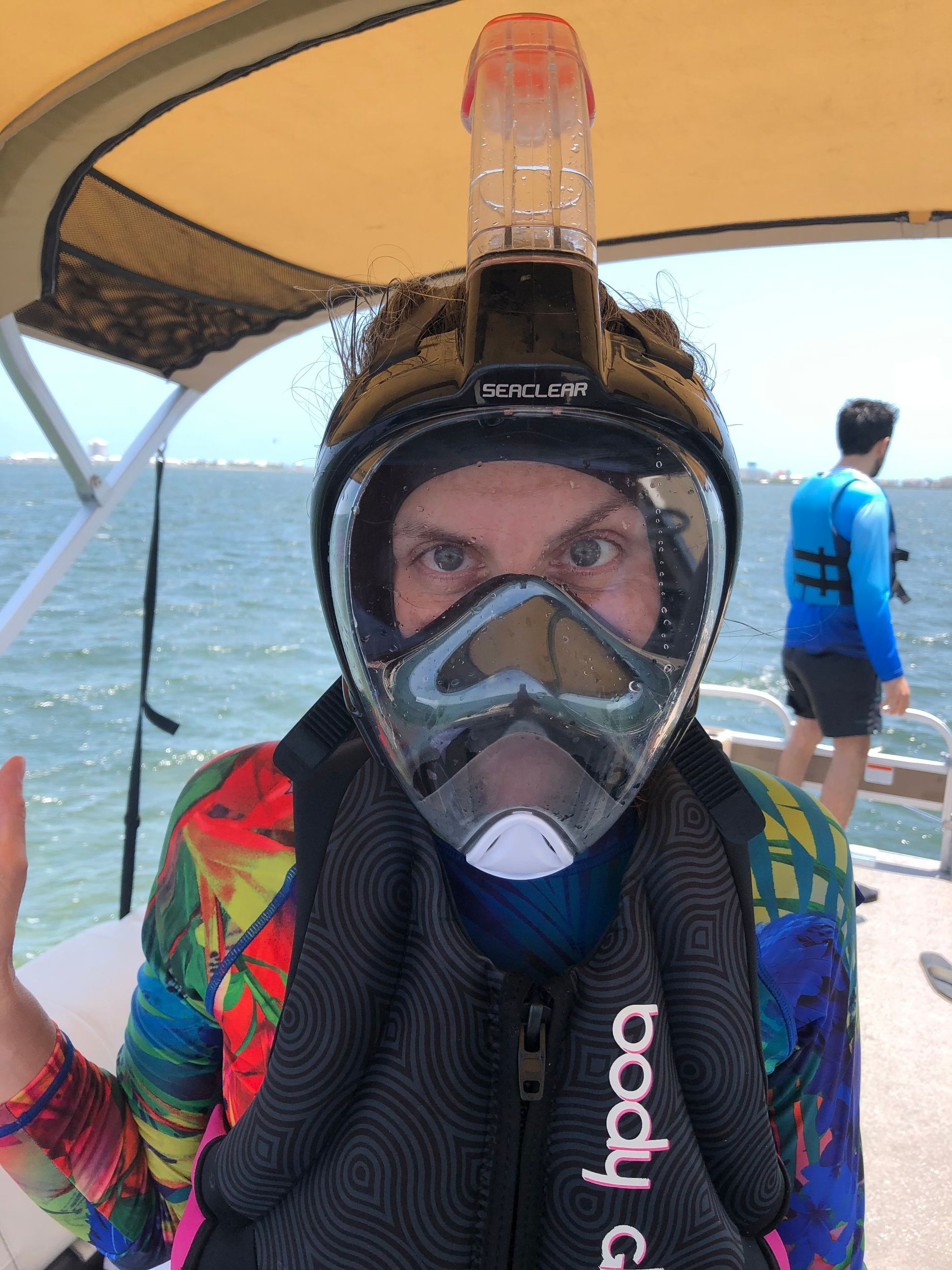 A person wearing a full face mask and goggles on a boat.