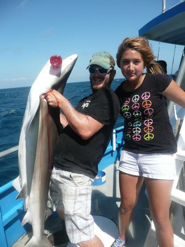 A man and a woman on a boat holding a shark