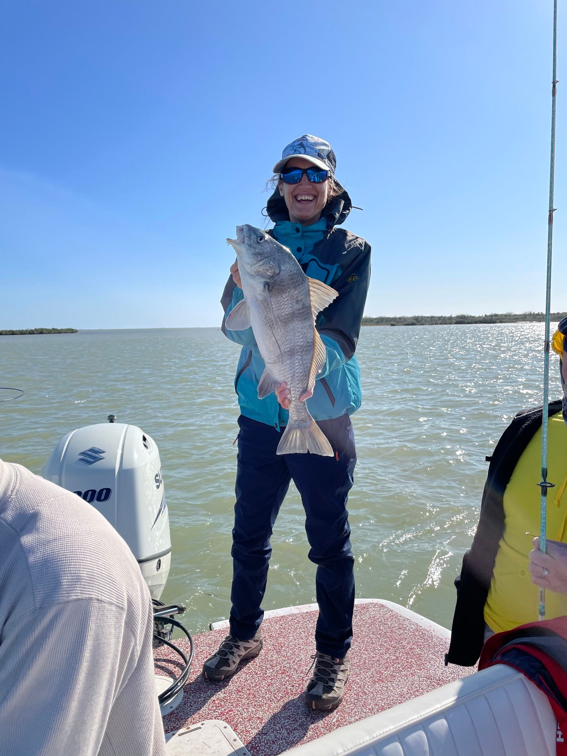 A woman is holding a large fish on a boat.