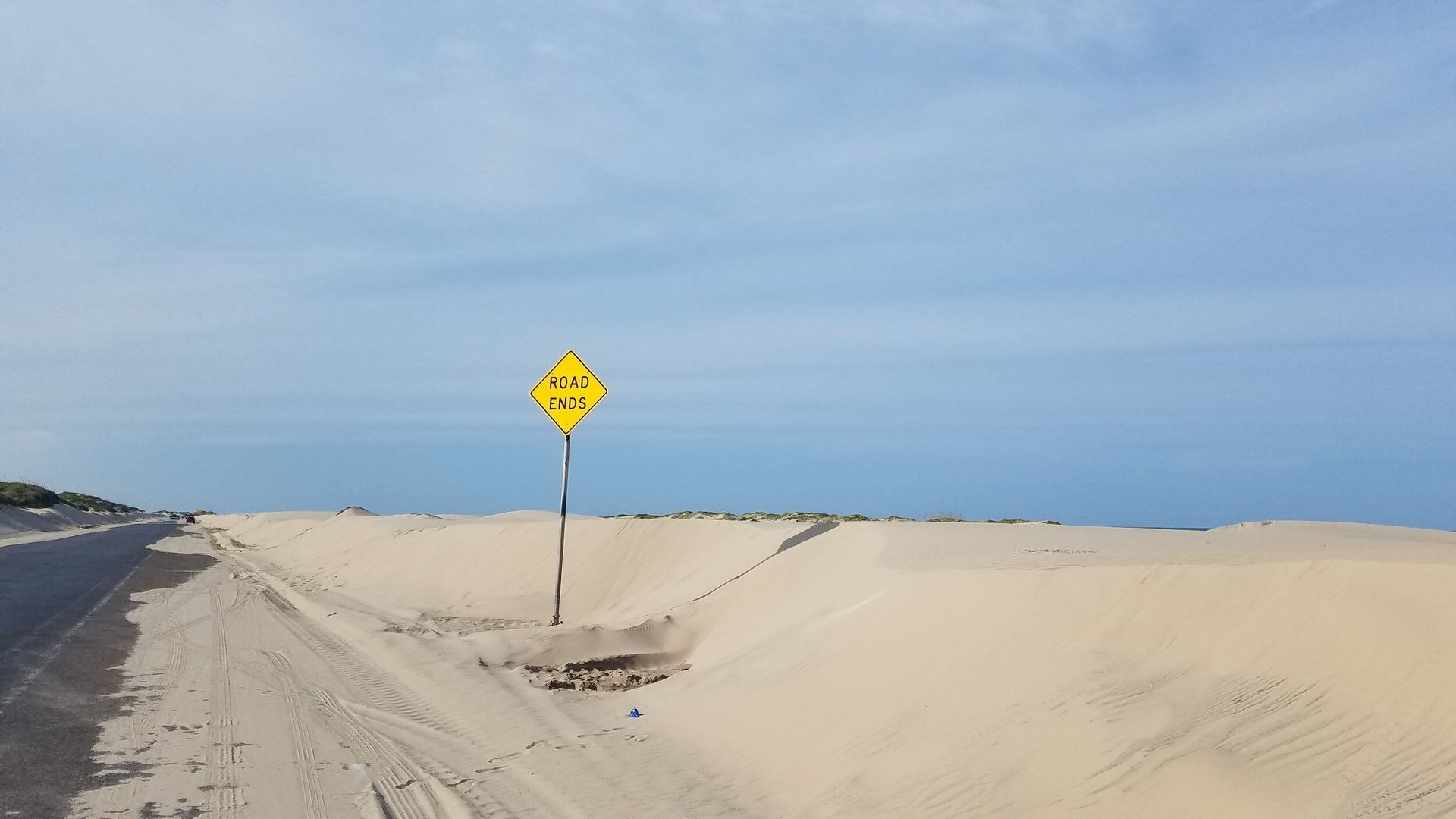 A yellow sign on a pole in the middle of a desert.