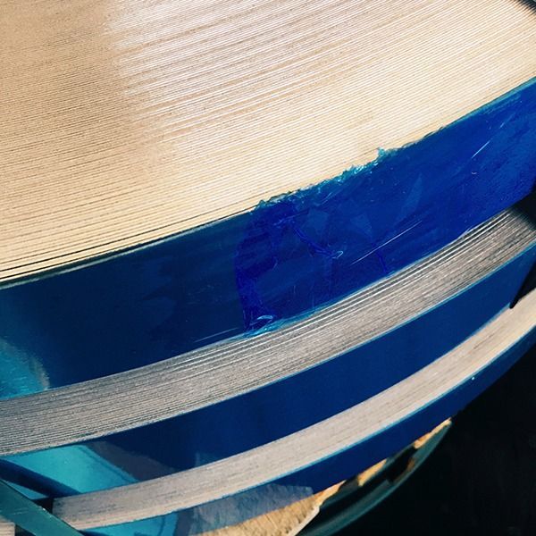 Rotolo arrotolato di metallo sottile e lucido, bordato di blu brillante.