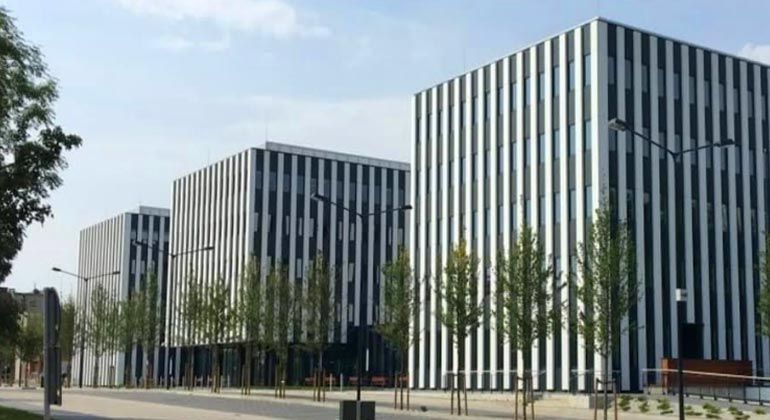 Tre moderni edifici per uffici con strisce verticali bianche e nere e alberi di fronte.