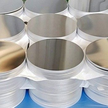 Pile di dischi di alluminio lucidi e circolari, probabilmente pezzi grezzi per la produzione.