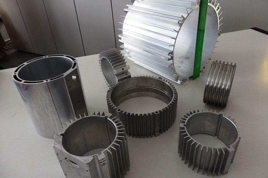 Assortimento di alloggiamenti motore in alluminio con alette di raffreddamento su una superficie bianca.