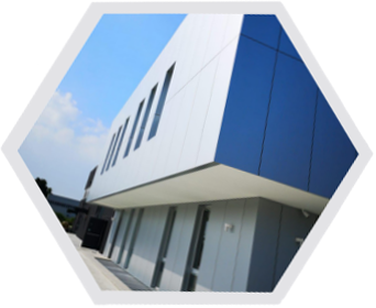 Edificio moderno con pannelli bianchi e blu, tetto piano e finestre rettangolari contro un cielo blu.