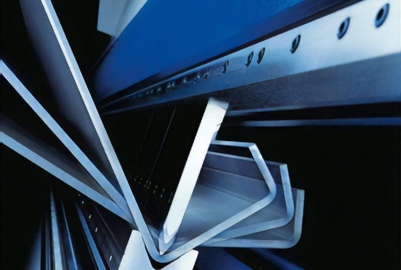 Lamiere piegate in una macchina industriale blu, che creano varie forme angolari.