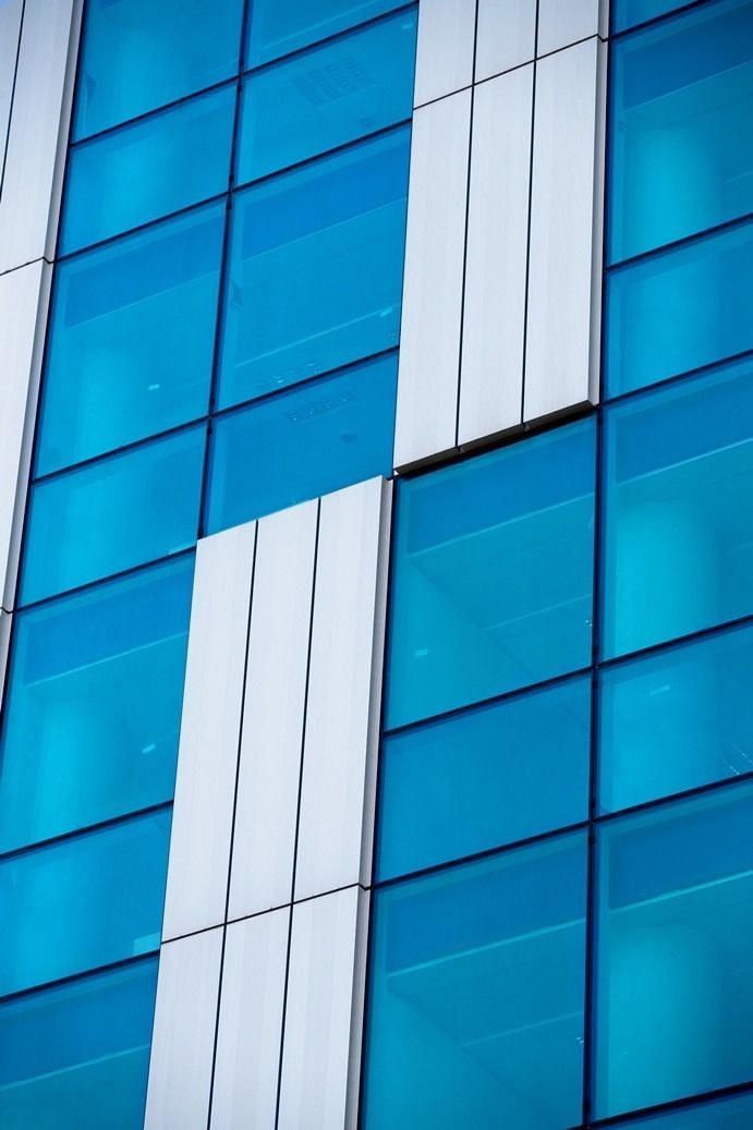 Facciata in vetro blu e bianco di un edificio moderno, con pannelli verticali.