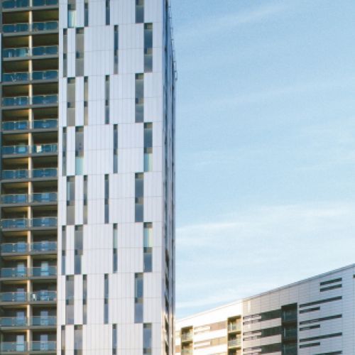 Moderni grattacieli residenziali con pannelli bianchi e argento che si stagliano contro il cielo azzurro.