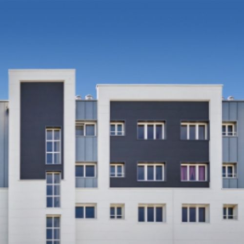 Facciata di un edificio moderno, bianca e grigia con accenti blu e cielo.