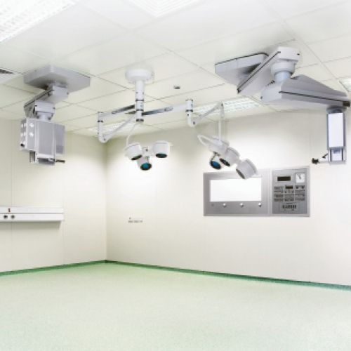 Una sala operatoria vuota con lampade chirurgiche sospese al soffitto. Pareti bianche, pavimento verde chiaro.