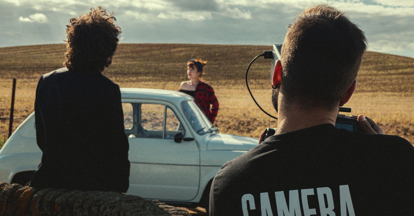 a person filming people at by a car