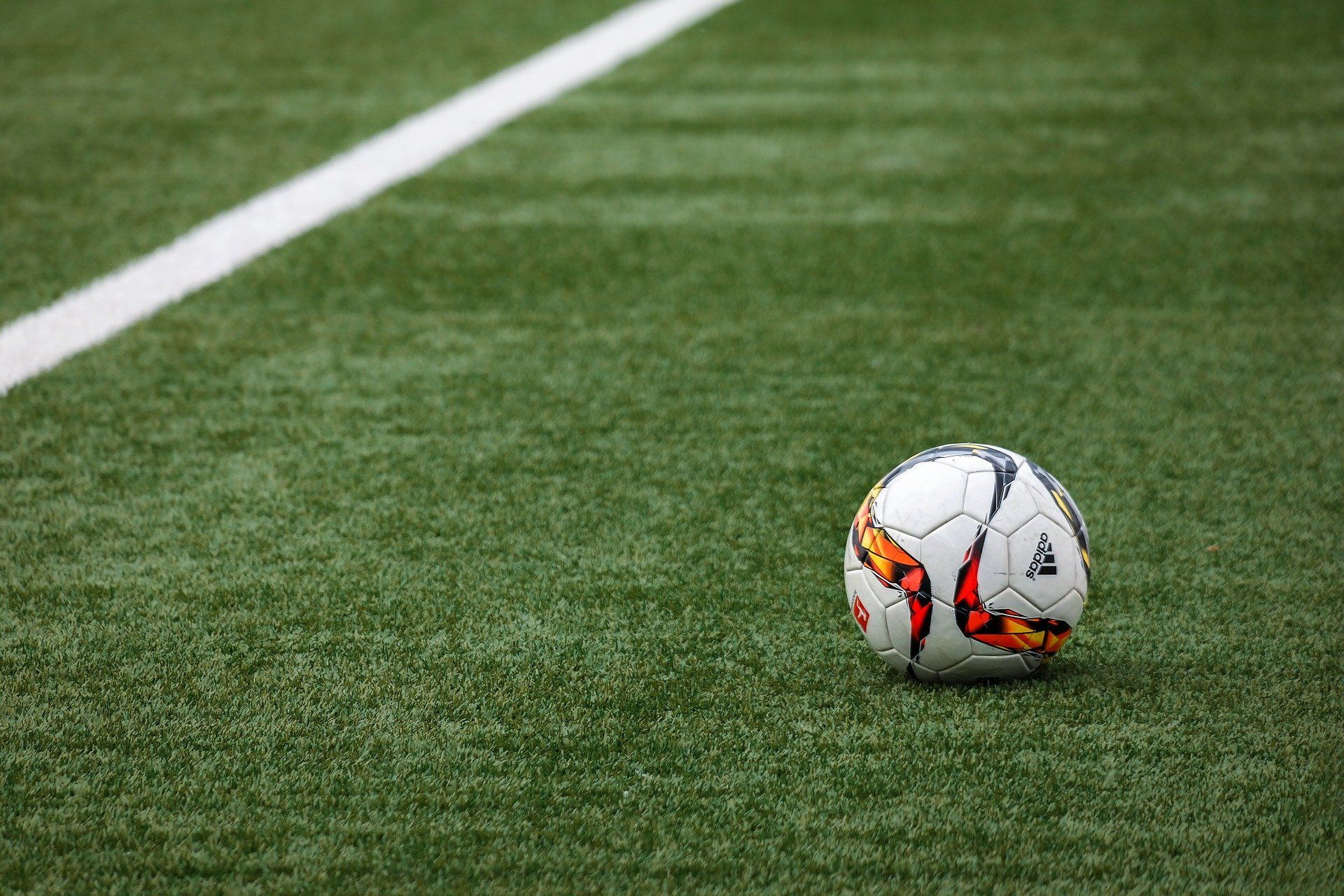 soccer ball laying on a soccer field made of synthetic grass