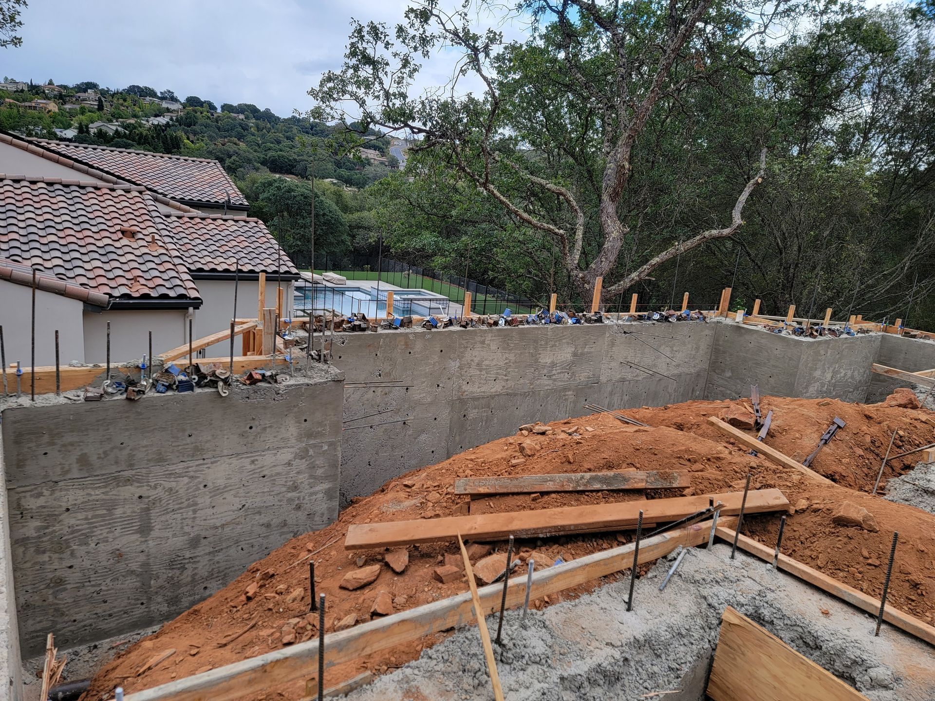 A concrete wall is being built on a hill in front of a house.