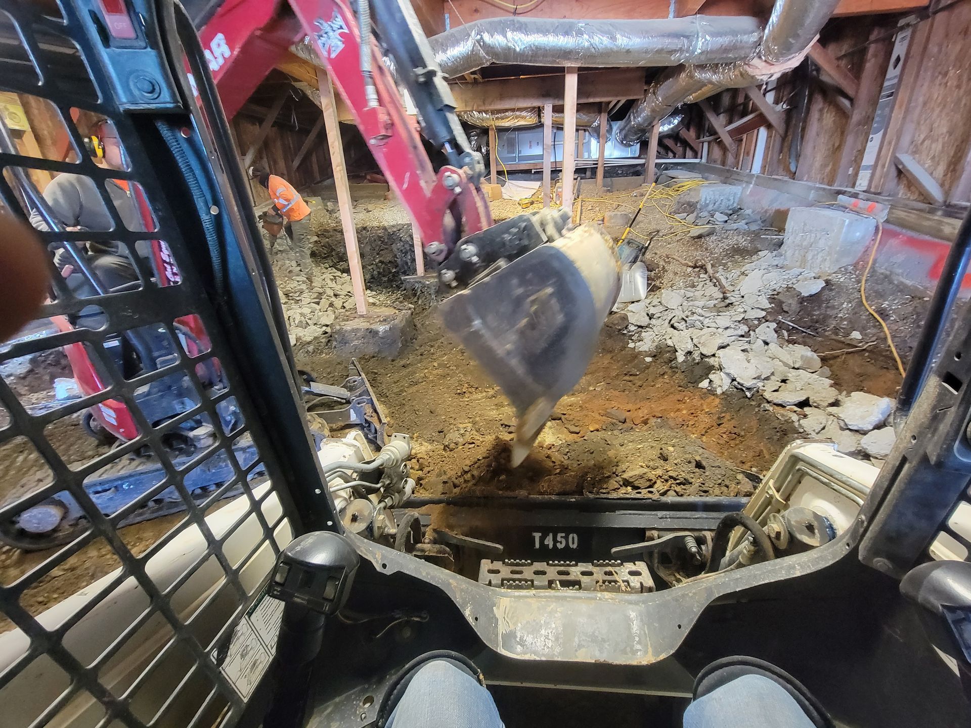 A person is driving a skid steer that is digging a hole