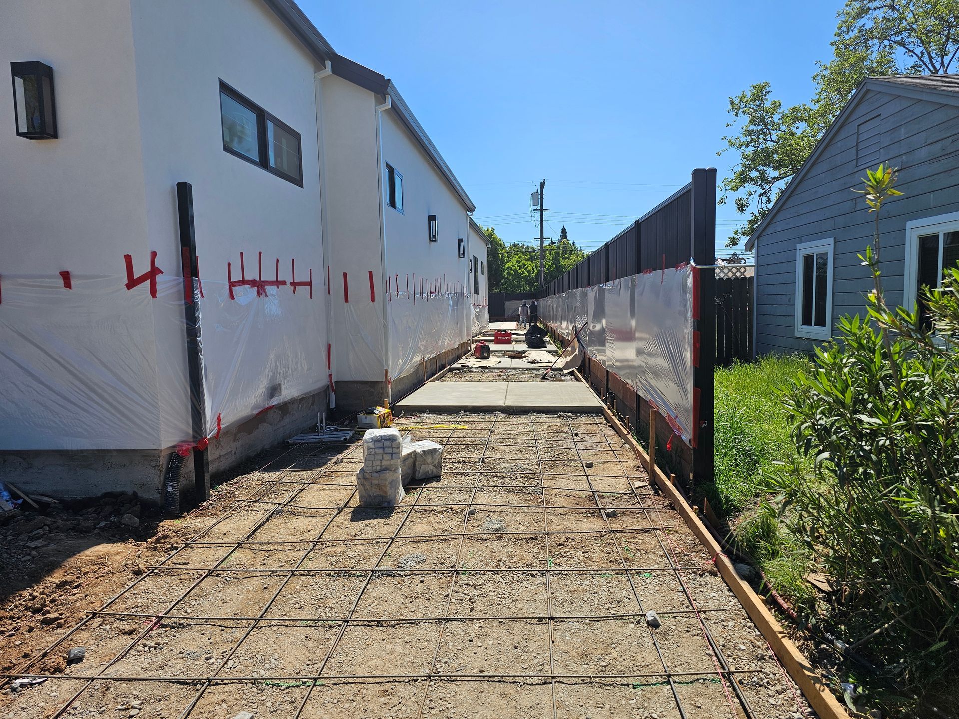 A concrete walkway is being built between two houses.