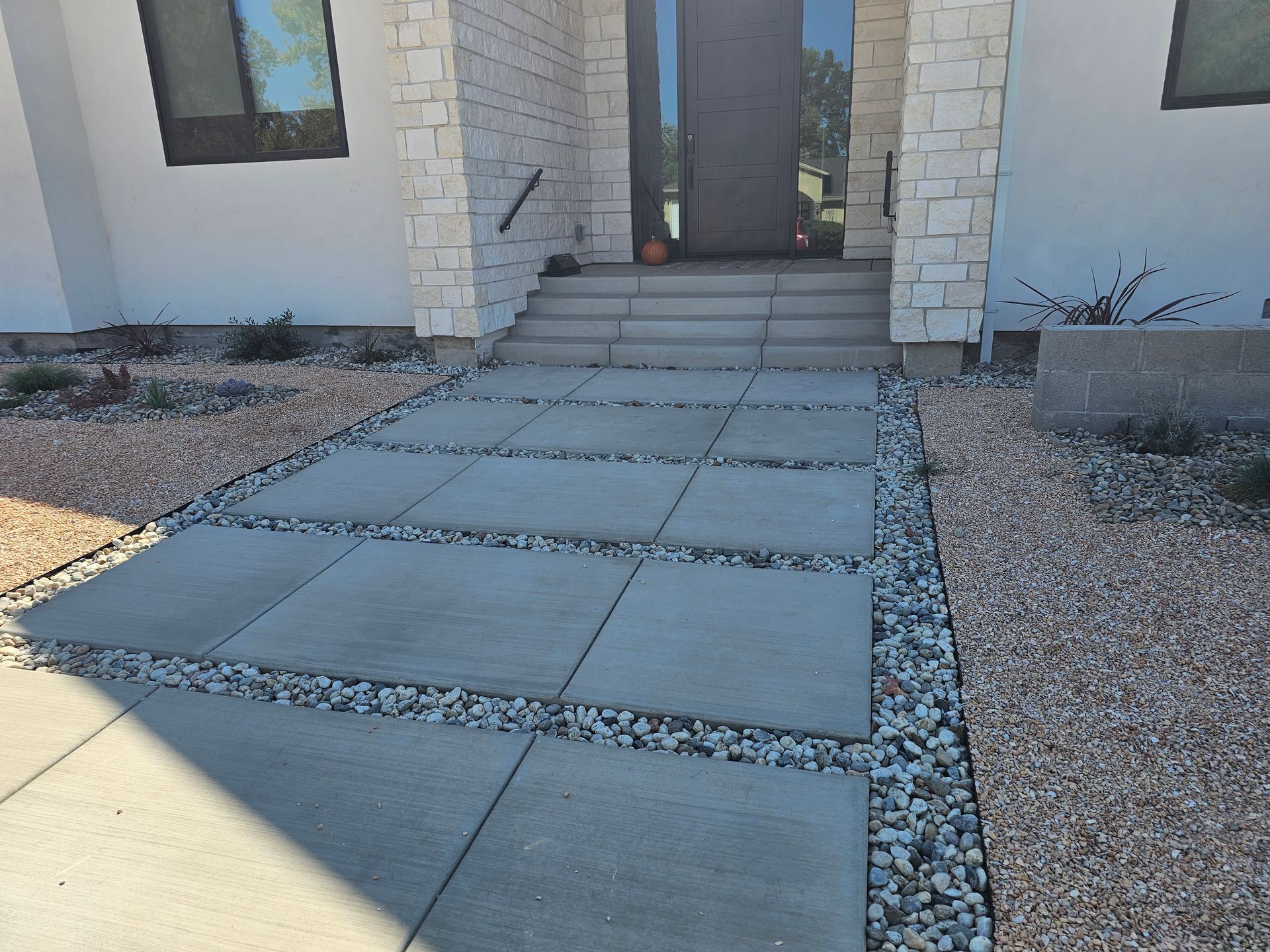 A concrete walkway leading to the front door of a house.