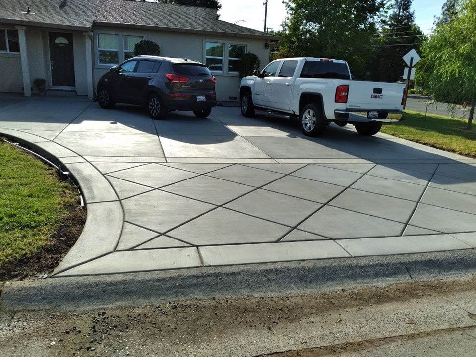 A concrete mixer is pouring concrete into a driveway in front of a house.