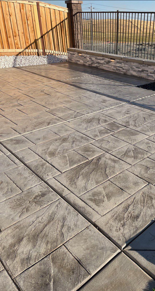 A concrete patio with a wooden fence in the background.