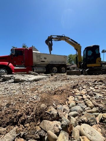A dump truck is being loaded with rocks by an excavator.