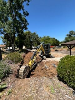 A yellow excavator is digging a hole in the ground.