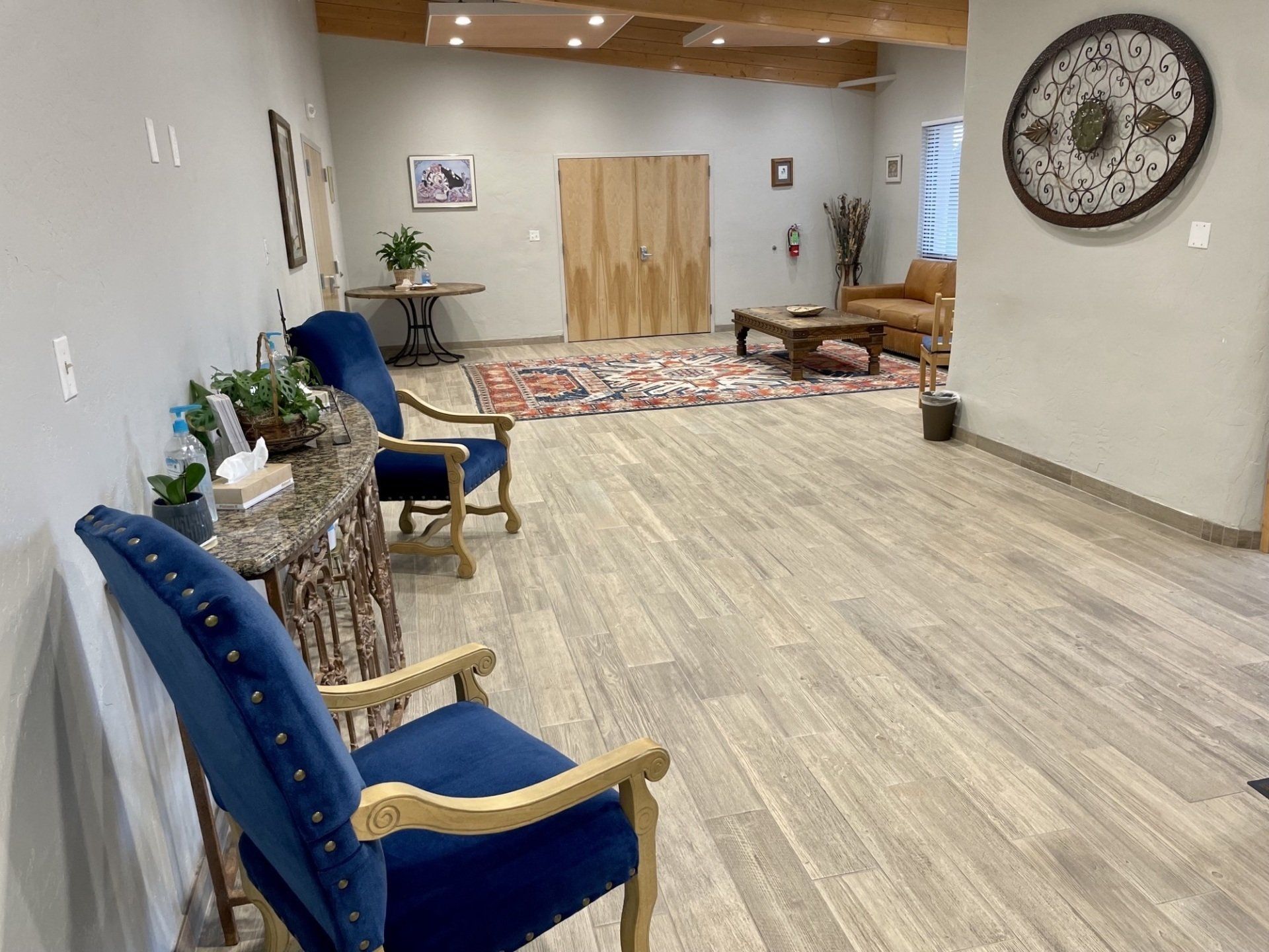Lobby with blue chairs, wood flooring, rug, and decorative wall art.