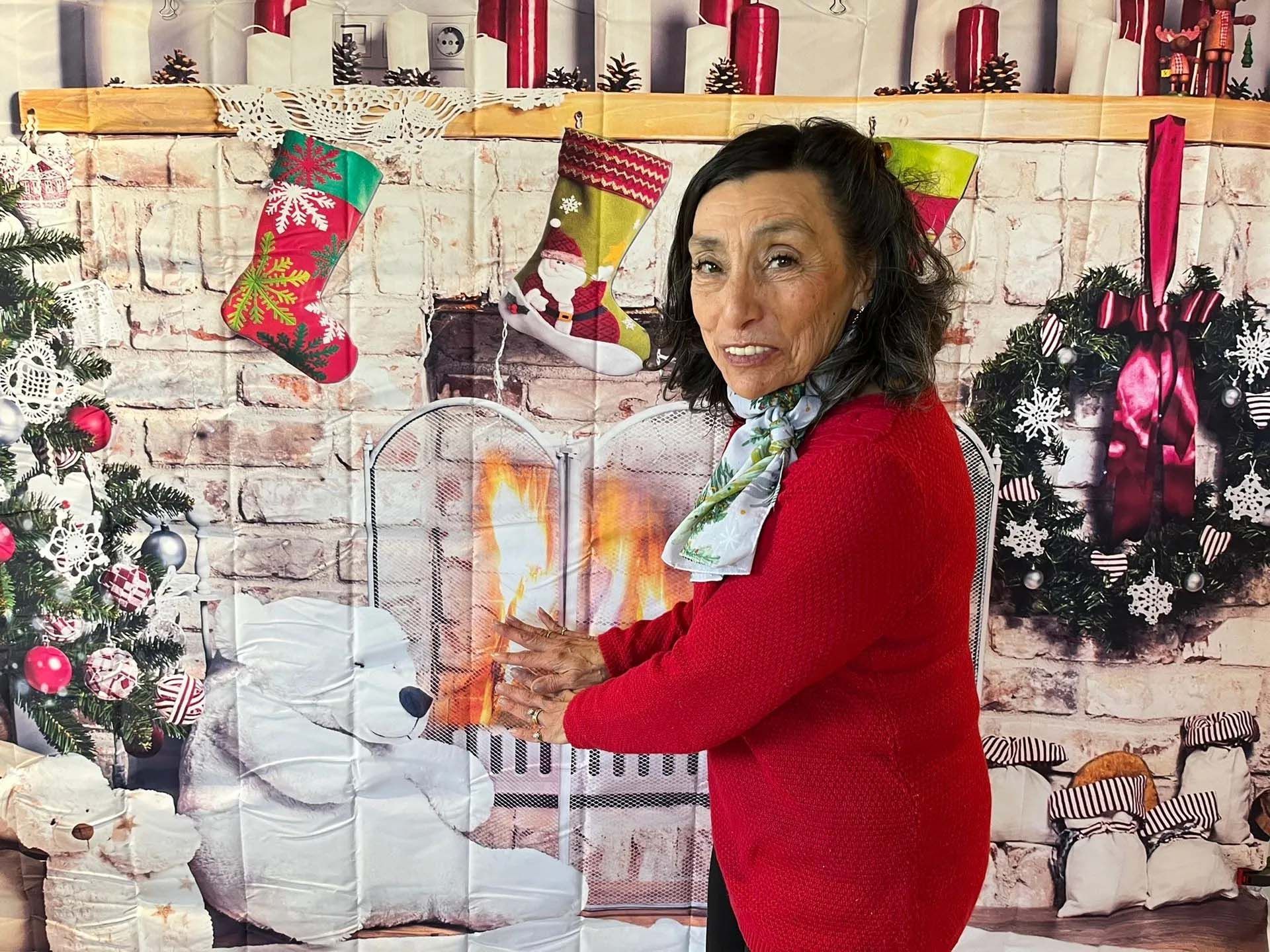 Woman in red sweater by a fireplace with Christmas decorations.