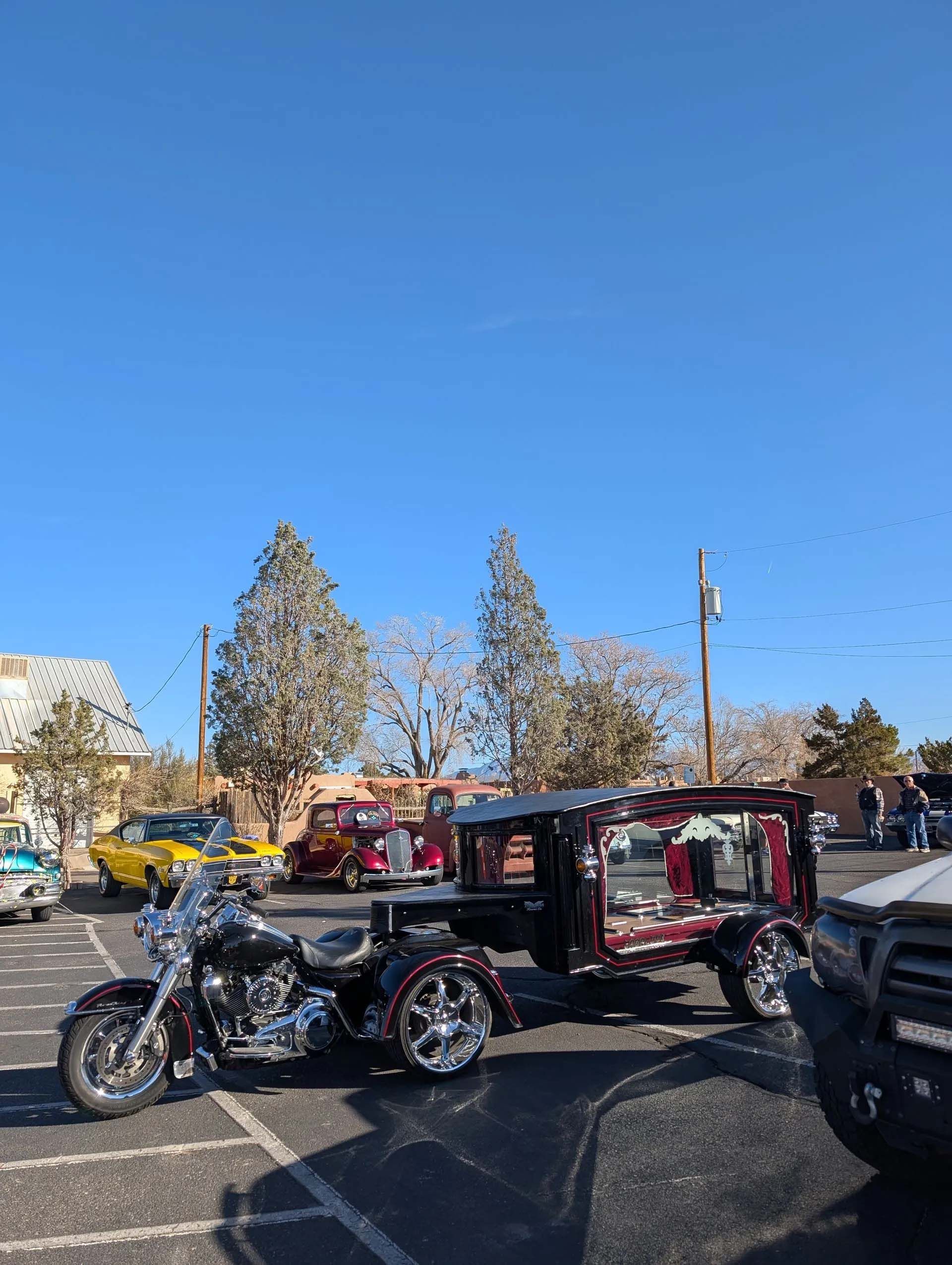 Motorcycle hearse with red trim, parked outdoors on a sunny day.