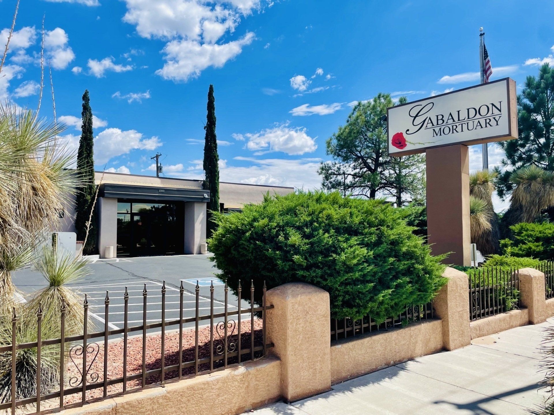 Rendering of a memorial with a central cross and surrounding structures, trees, and sky.