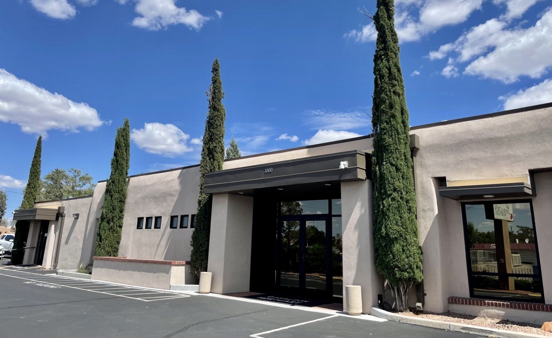 Aerial view of a green park with trees and roads. Cars are parked near the entrance.