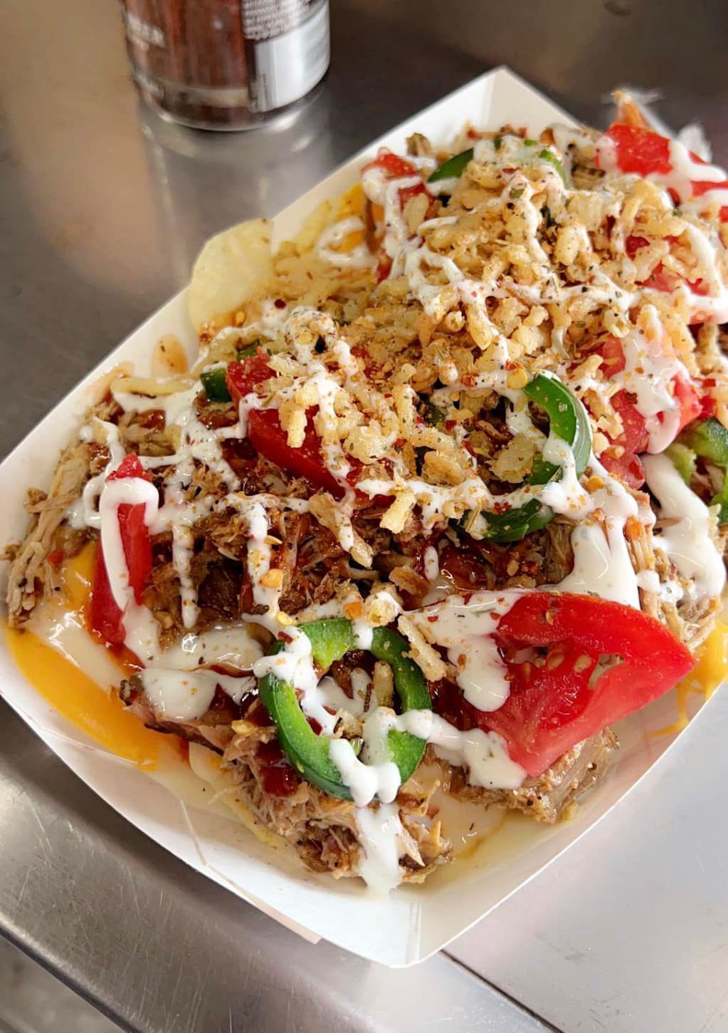 A paper tray filled with a variety of food on a table.