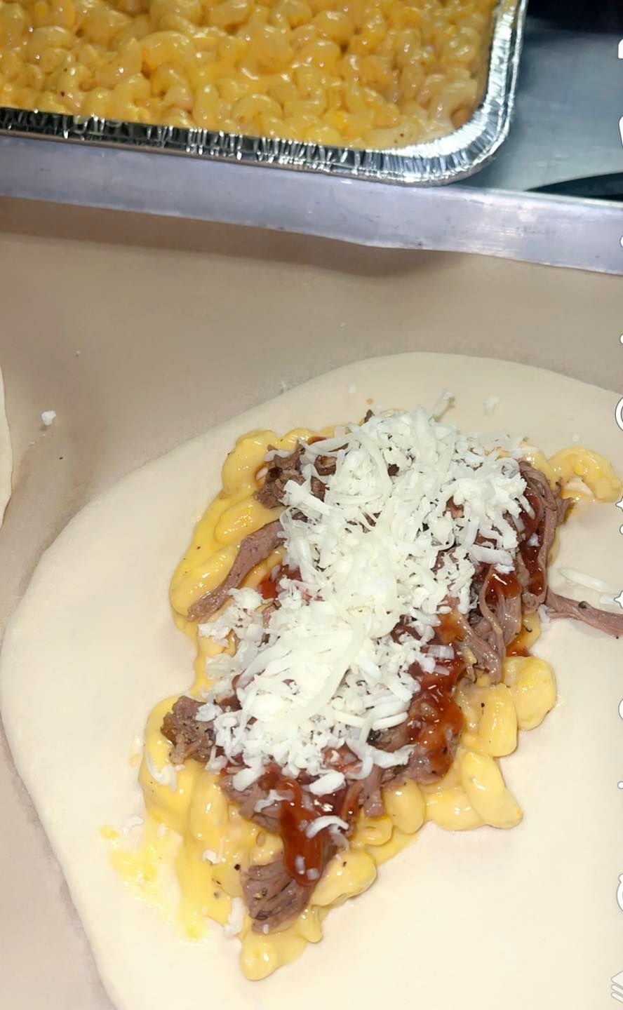 a white plate topped with macaroni and cheese and meat .