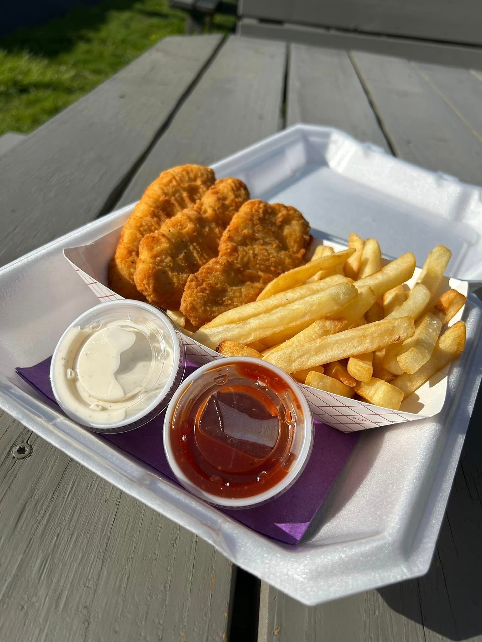 A styrofoam container filled with chicken nuggets and french fries.